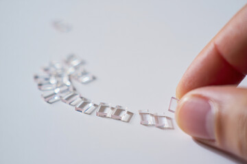 Arrangement of Tiny Glass Pieces Being Assembled by Hand on White Surface for Arts and Crafts with Light Reflection and Shadow