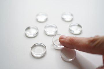 Person Arranging Transparent Glass Stones on White Background Close Up in Studio for Creative Composition 150 Characters