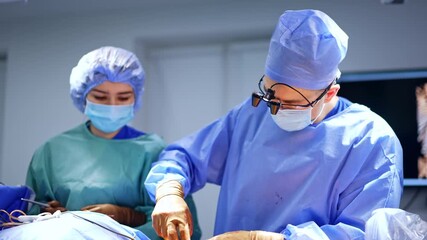 Male surgeon and female scrub nurse stand at the patient. Neurosurgeon performs surgery in modern hospital.