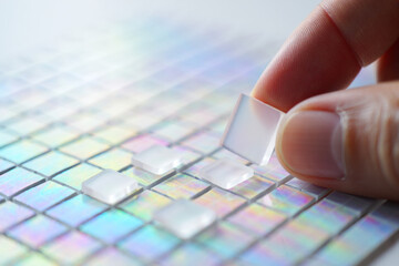 Index Finger Placing Transparent Square Tile on Multicolored Grid Surface Close Up 150 Characters