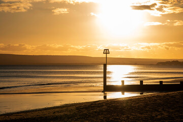 Evening orange Winter sun setting behind a groyne on Bournemouth beach