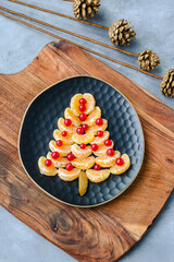 Tangerine Christmas tree with red currants. Funny food for kids. Christmas food background