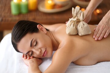 Woman enjoying herbal compress massage for relaxation and wellness therapy