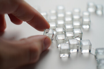 Hand touches clear ice cube structure showing connectivity and technology on white plain background