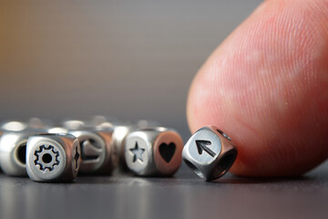 Close up of hand touching metal charm dice bead with arrow up icon on grey surface