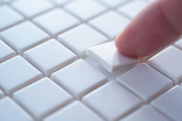 Hand Picks Up One White Tile from Square Tiles Representing Selection Decision or Problem Solving 150 Characters