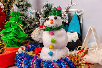 A snowman sitting on top of a table covered in tinsel