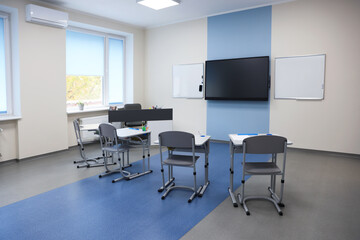 Stylish classroom with desks, chairs and tv at school
