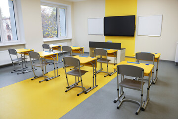 Stylish classroom with desks, chairs and tv at school