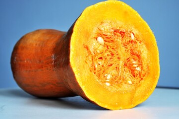 A close-up image of a fresh, sliced pumpkin showing its bright orange flesh, seeds, and natural texture.