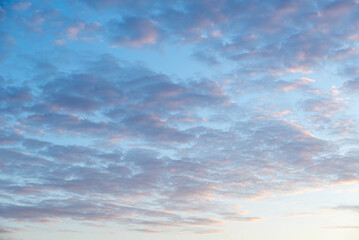 Soft pastel hues blend in the sky as clouds gather at sunset, creating a serene atmosphere over the quiet landscape during evening hours