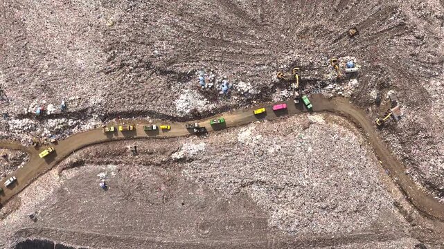Aerial top view of A Huge Waste, garbage, dump, rubbish landfill. A landfill compactor, group of workers sort out the garbage in the landfill. Trash trucks dump waste polluting products.
