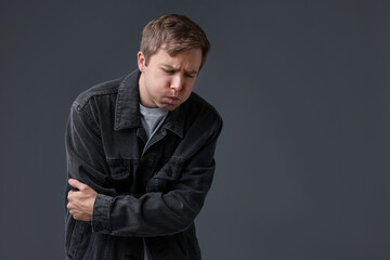 Obraz premium Young man suffering from nausea and stomachache on grey background, space for text