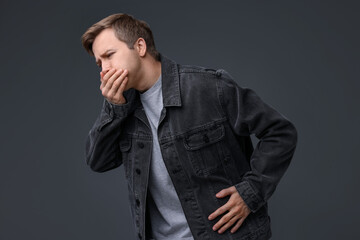 Fototapeta premium Young man suffering from nausea and stomachache on grey background
