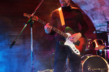 Man playing electric guitar on stage with smoke, closeup