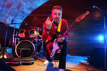 Obraz premium Man with electric guitar showing rock gesture on stage
