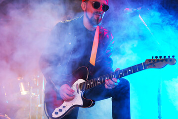 Man playing electric guitar on stage with smoke