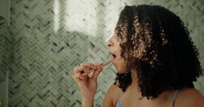 African woman, brushing teeth and hygiene in bathroom for fresh breath, dental care and wellness. Person, toothbrush or cleaning mouth to remove plaque, prevent gingivitis and morning routine in home