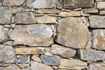 natural stone wall showcases a mix of different rock shapes and tones, creating a rustic appearance perfect for outdoor environments. Ideal for landscaping or architectural use