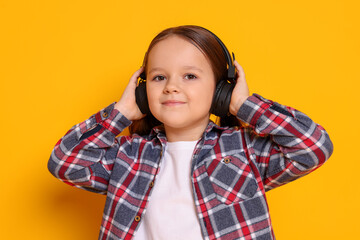 Cute little girl in headphones on orange background