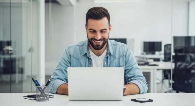 Smiling man working on laptop in modern office environment