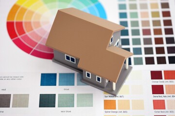Small toy house and papers with color palette samples. Concept of interior and exterior design and...