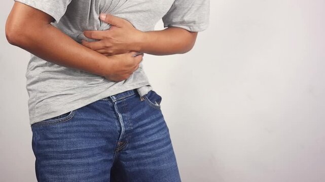 Stomach cramps, stomach aches, and other stomach ailments. A man's hands wrapped around his stomach indicate unbearable pain and injury in the abdominal area. Holding in a bowel movement.
