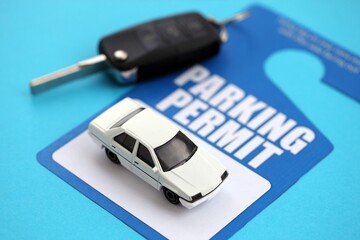 Parking permit paper notice tag for car interior with ignition keys and toy car. Parking permit for people with disabilities concept