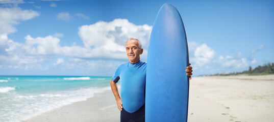 Mature man in a wetsuit holding a surfboard