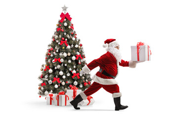 Santa claus carrying a present and running by a christmas tree