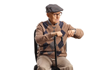 Elderly man sitting in an office chair and checking his watch