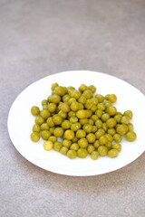 Green canned peas on a white plate