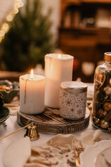Three white candles with snowflakes on a table with a white tablecloth.