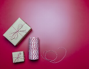 Gifts wrapped in brown paper and tied with red and white string on red background.