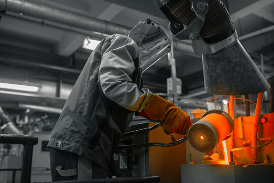 Industrial worker shapes glowing metal with specialized tools amidst a factory setting. - Powered by Adobe