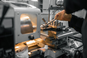 A worker adjusts a precision machine tool with focused attention amidst industrial equipment.