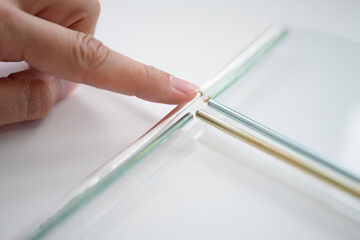 Index finger points intersecting metal rods on pristine white surface in close up shot suggesting precision engineering and modern architecture