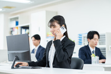 Fototapeta premium オフィスで電話する若いビジネスウーマン