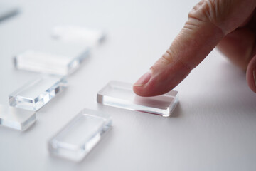 Finger Touching Rectangular Clear Acrylic Blocks on White Table, Concept for Modern Design and Artistry with Mockup Space 150