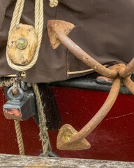 Fototapeta premium Grapnel anchor resting on red and white boat hull
