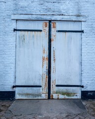 Rusty metal doors protecting white brick wall building