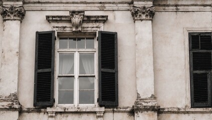 An aged government building with a contrasting black and white window shutters on opposite sides