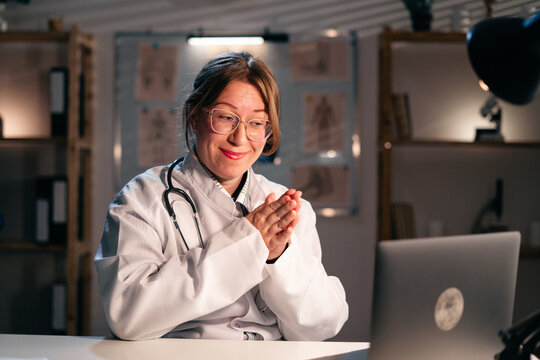 Female Doctor in white uniform Using Laptop In Hospital pray to God working late during night shift giving Medical Advice.