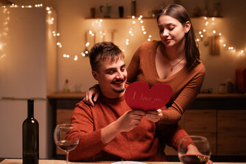 Young couple in love celebrating Valentine's Day have romantic dinner, talking spending time together. Husband and wife in warmth atmosphere in the kitchen