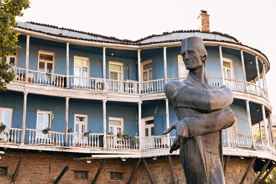 1 November 2025, Tbilisi, Georgia: Shota Rustaveli monument in a park setting, with traditional blue balconied houses in the background