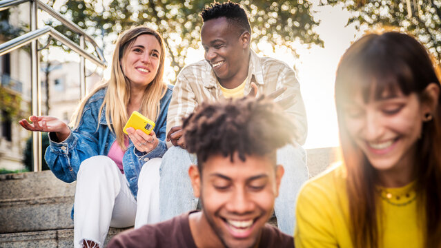Group of young people using smart mobile phone outdoors - Happy friends with smartphone laughing together watching funny video on social media platform - Tech and modern life style concept