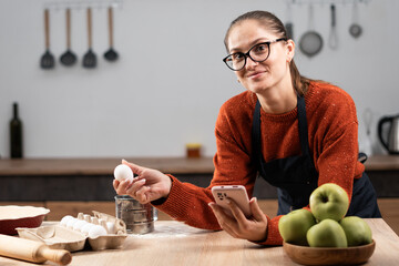 young woman making dough baking at the kitchen, searching online recipe book
