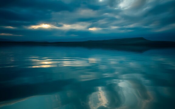Calm blue water with cloudy sky and mountain in the distance - Powered by Adobe