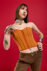Stylish young woman poses confidently against a vibrant red background for a fashionable showcase