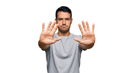 Serious man showing his hands and signaling stop isolated on transparent background he is wearing a gray tshirt and has a determined expression